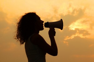 beautiful woman holding megaphone and shouted into it at sunset